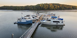 boats docked at pier in the early morning with trees on the opposite shore.